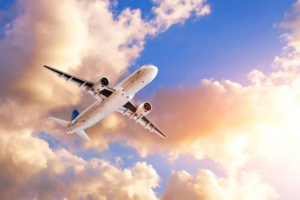 夕方の雲を背景に旅客機を飛ばす太陽に照らされた。観光、休暇、旅行の概念. — ストック写真