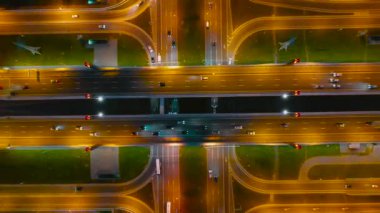 Karayolu ve yol kavşağı ile büyük köprü gece fenerler tarafından aydınlatılmış, asfalt işaretleri görünür, gece havadan üst görünümü