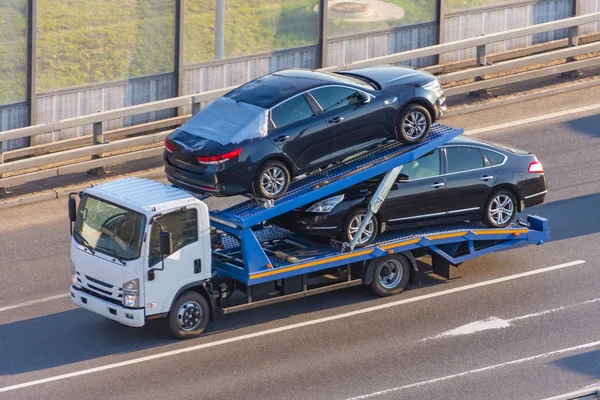 Twee crash auto geladen op een sleepwagen voor vervoer, snelweg afgeleverd op de bestemming. — Stockfoto