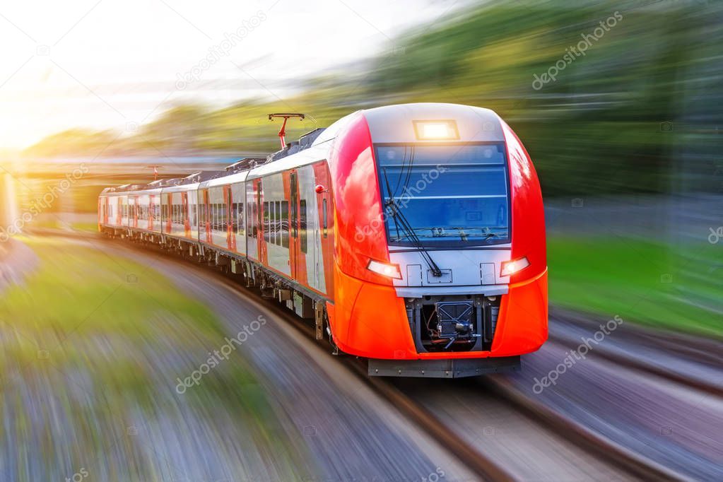 Passenger electric train rides at high speed on the turn of the railway line.