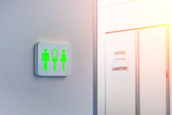 Değil işgal tuvalet işareti yeşil işaretlenir, arka plan karşı uçağın içinde wc bir kapı. — Stok fotoğraf