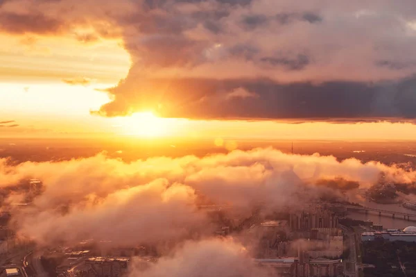 Bela vista aérea pôr do sol sobre a cidade e baixas nuvens flutuantes eo sol brilhante no horizonte . — Fotografia de Stock
