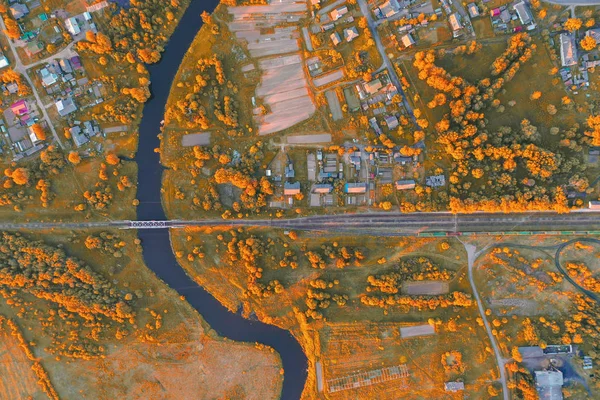 Şehir arasında dolambaçlı küçük nehir havadan görünümü sonbahar manzara, turuncu renklerde akarsu doğa alanı, üst görünümü. — Stok fotoğraf