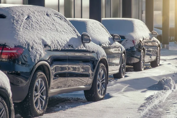 Parkeerplaats met auto 's zonovergoten bedekt met verse sneeuw. — Stockfoto
