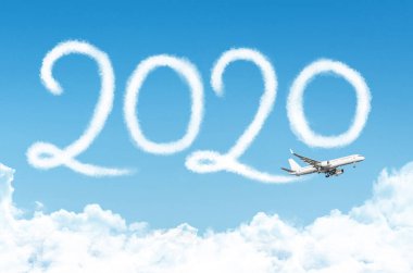 Arka planda bulutların altında 2020 konsept seyahatiniz kutlu olsun. Yolcu uçağı buharı tarafından çiziliyor gökyüzünde.