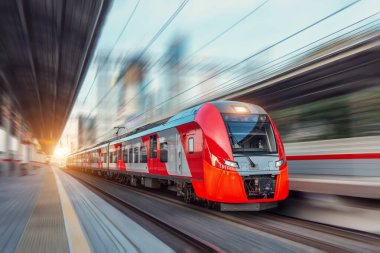 Elektrikli yolcu treni şehir manzarası arasında yüksek hızda yol alır.
