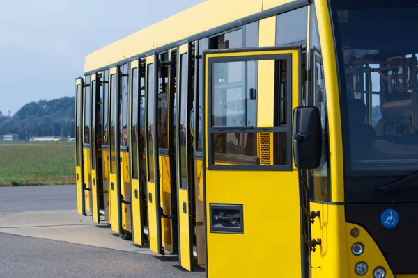 乗客が空港で飛行機に輸送するのを待っているオープンドア付きの黄色の旅客バス. — ストック写真