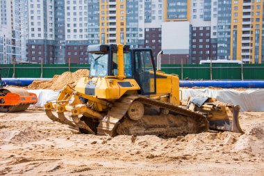 Yol altında kanalizasyon ve ısıtma iletişiminin inşası üzerine yoğun buldozer, çok katlı konut binaları arasında