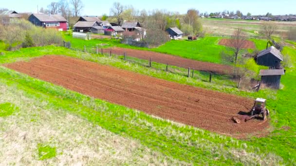 農業用トラクターは 野菜を植えるための畑に土地を耕し 種を播く春鳥カラスやジャックドウを飛んでいます 空中風景 — ストック動画