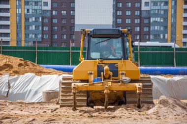 Yolun altındaki kanalizasyon ve ısıtma iletişiminin çok katlı konut binaları arasında ağır buldozer manzarası