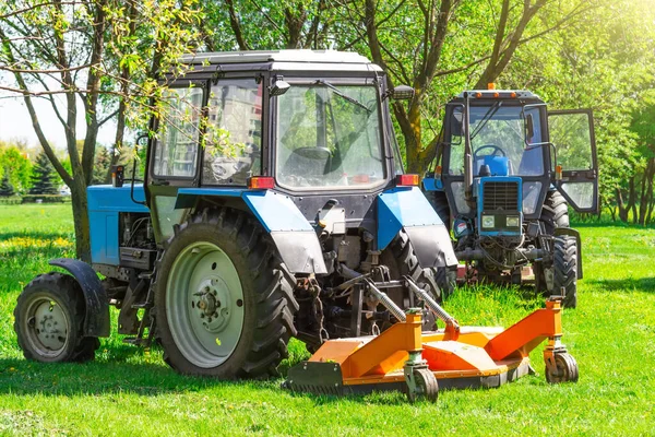 トラクターは市の芝生に草を刈るためにトレイル芝刈り機を使用しています — ストック写真