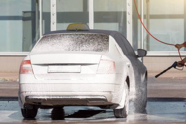 Araba, ekspres oto yıkamaya başvurmak için tabancadan köpükle kaplı.