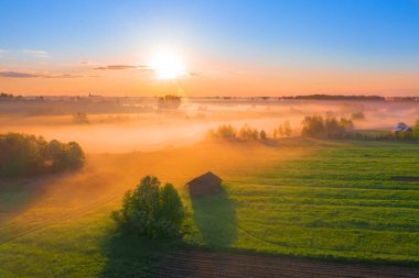 Ovanın ve nehir taşkın ovasının üzerinde sis sabahı kırsal bir köyün yakınındaki çayırda bir ev, hava manzaralı bir yer.