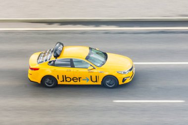 Sarı yolcu vagonu Uber Taksi otoban manzarasında ilerliyor. Rusya, Saint-Petersburg. 20 Mayıs 2020
