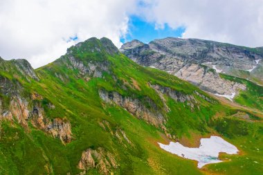 Yeşil çayırları, karlı taşları, dereleri olan kayalık bir dağın tepesinde. Hava aracı görünümü