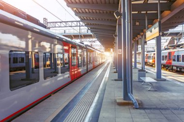 Banliyö ekspres treni istasyondan ayrılıyor, boş bir platform.