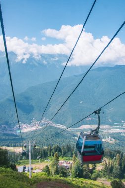 Tepenin yamaçlarındaki dağ ormanının yukarısındaki teleferiğin kulübeleri.