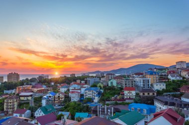 Tatil köyünün manzarası deniz kıyısındaki pek çok ev akşam saatlerinde uzak dağlarda.