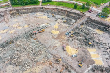 Yıkılmış bir binanın şantiyesinde çalışan kazıcılar. Çimento kalıntılarını ezici ekipmanlara yüklüyorlar ve toprağı taşıyorlar.