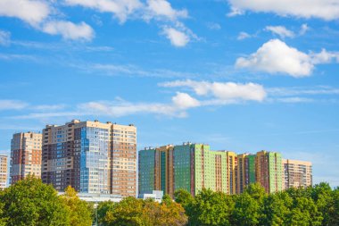 Genç meşeler ve söğütlerle dolu yeşil yaz parkı. Arka planda, çok katlı binalar nüfus için ekolojik olarak temiz bir alan.