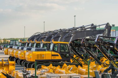 New Excavators are lined up in a parking lot clipart