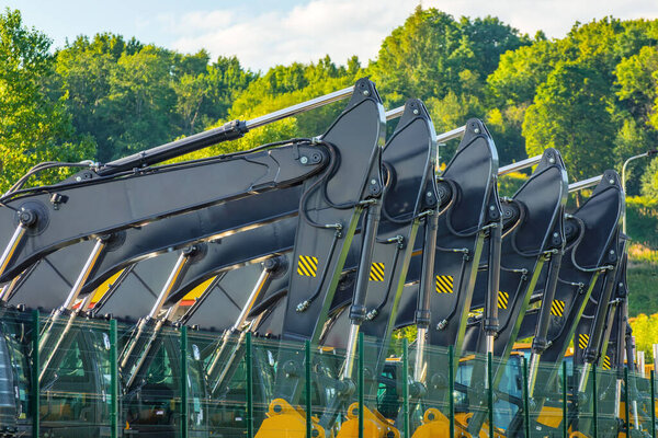 New Excavators boom with bucket are lined up in a parking lot