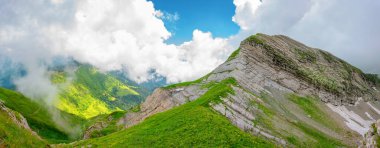 Alp çayırları ve panorama manzaralı kayalık bir tepenin üstünde.