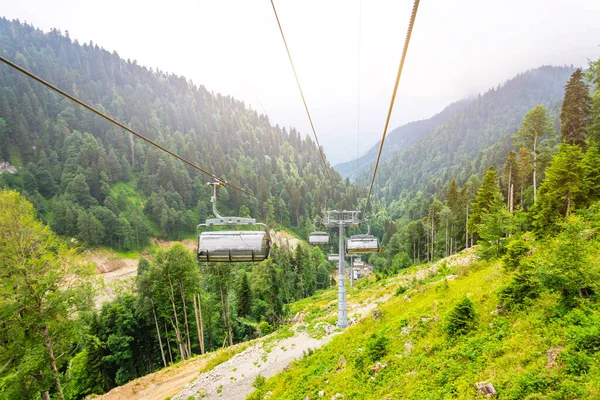 Cable car path in the mountains on the slope of the peak in the summer forest, perspective view