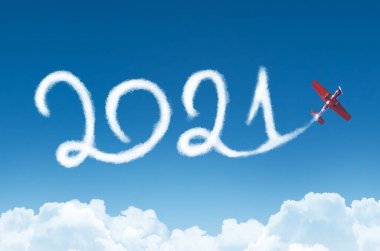 Arka planda bulutların altında 2021 yılınız kutlu olsun. Yolcu uçağının çizdiği beyaz buhar gökyüzünde iz bırakıyor