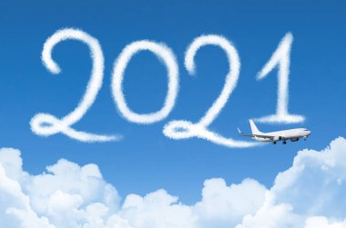 Arka planda bulutların altında 2021 konsept seyahatiniz kutlu olsun. Yolcu uçağı buharı tarafından çiziliyor gökyüzünde