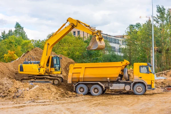 城市道路建设中的黄色卡车 挖掘机装载砂土 — 图库照片