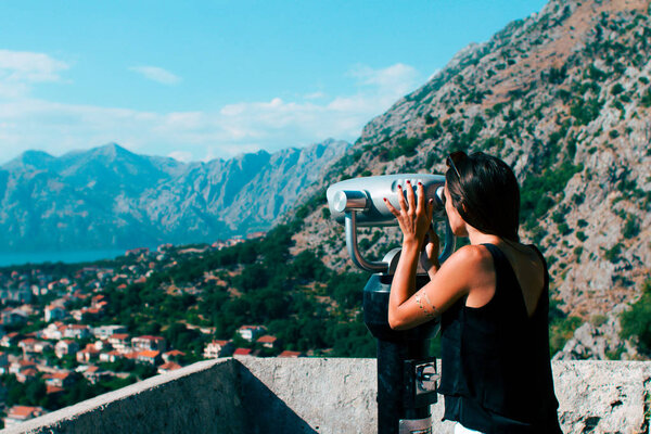 back view of young stylish woman posing outdoors near beautiful Montenegro mountains