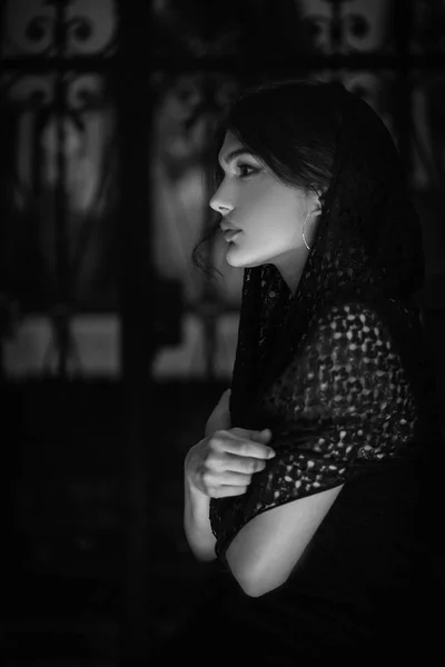 close-up photo of young brunette woman with scarf on head in church, black and white