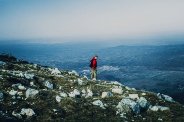 Açık havada dağlarda kırmızı ceketli genç adam fotoğrafı 