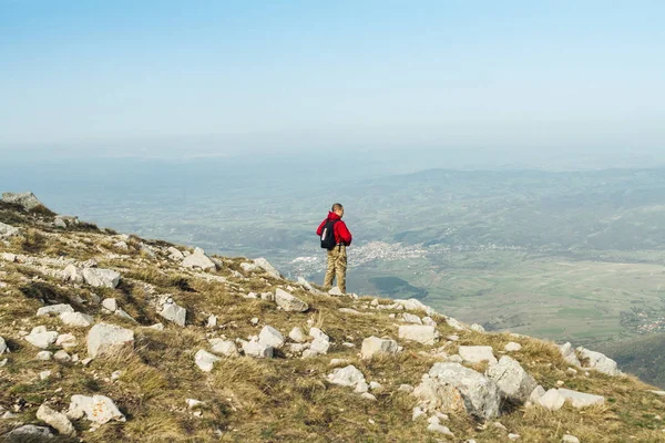 Açık havada dağlarda kırmızı ceketli genç adam fotoğrafı 
