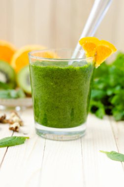 Ispanak, kivi ve hafif ahşap masa üzerinde bir bardak portakal ile sağlıklı yeşil smoothie