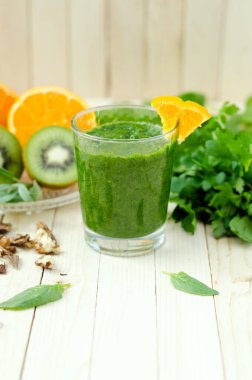 Ispanak, kivi ve hafif ahşap masa üzerinde bir bardak portakal ile sağlıklı yeşil smoothie