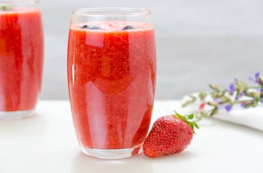 Taze çilek meyve ve smoothies beyaz üstüne iki bardak. Yaban mersini ve çilek.