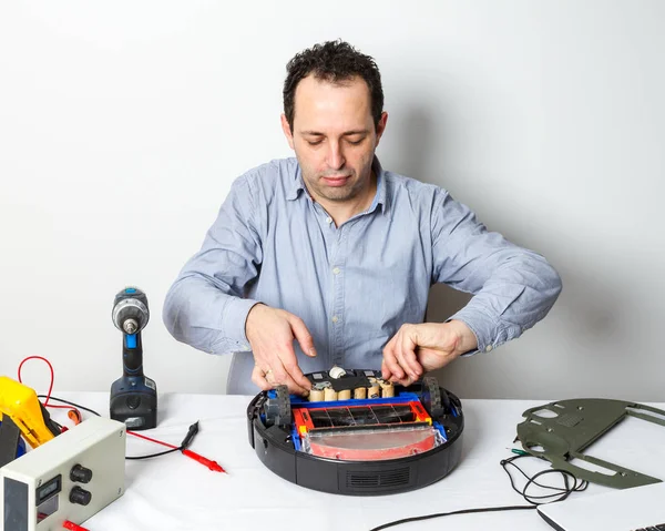 Repairman changing batteries on robotic vacuum cleaner. Repairing robot cleaner