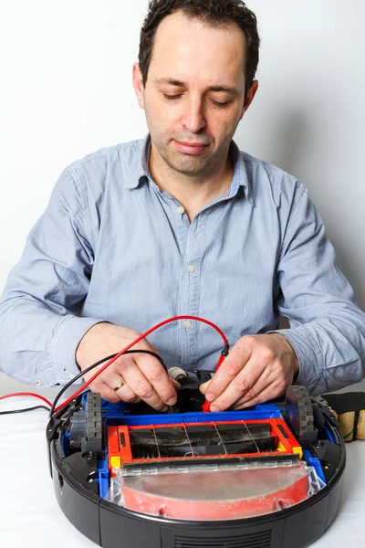 Man changing batteries on robotic vacuum cleaner. Repairing robot cleaner