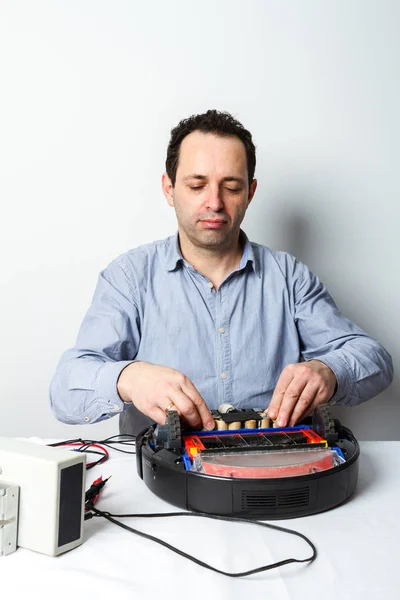 Portrait of professional repairman changing batteries on robotic vacuum cleaner. Repairing robot cleaner