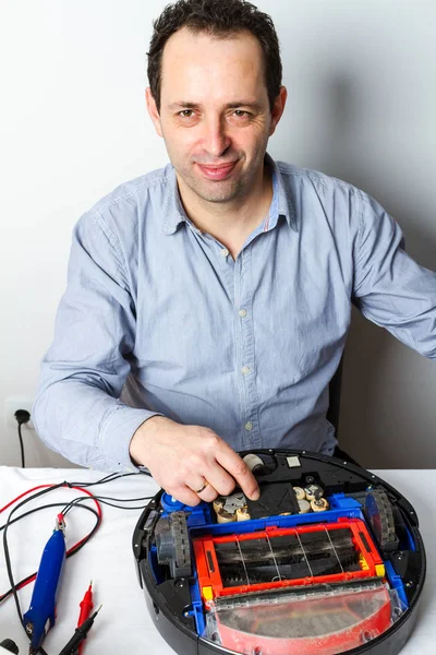 Portrait of professional repairman changing batteries on robotic vacuum cleaner. Repairing robot cleaner