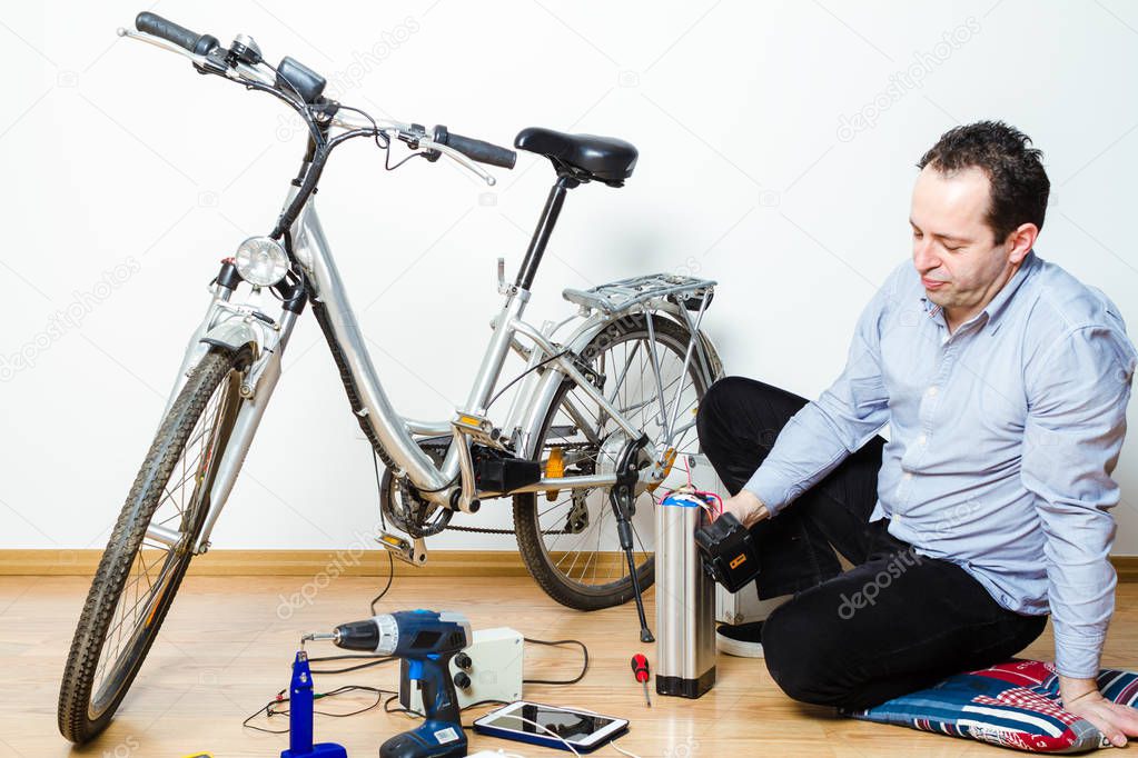 Mechanic repairing battery powered bicycle in his workshop