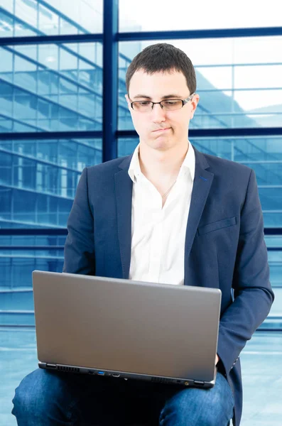 年轻的商人戴着眼镜 用膝上型电脑在机场看着笔记本电脑 — 图库照片