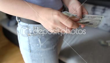 Bir kadın bir yeni 100 ABD Doları banknot onun cebine koyarak closeup