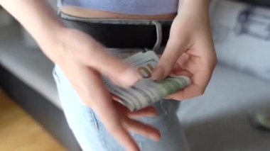 Bir kadın bir yeni 100 ABD Doları banknot onun cebine koyarak closeup