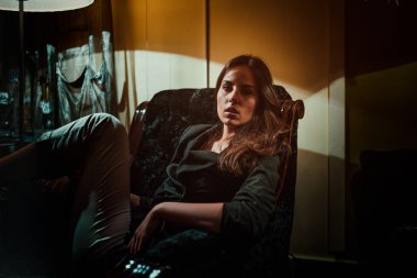 Genç ve güzel bir kadın evde koltukta, rahatlatıcı portresi 