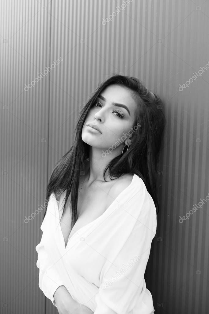 Black and white portrait of beautiful young girl standing against the wall