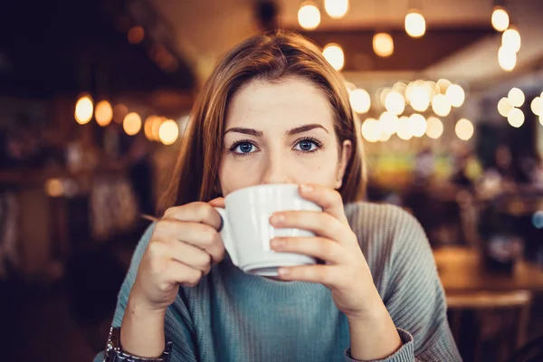 young and beautiful woman with cup of coffee in cafe