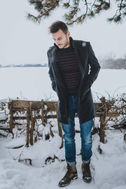 Kışın kar kucaklayan genç çekici adam.